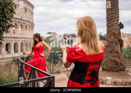 Frau, die ein Foto von einem Freund in rotem Kleid in der Nähe des Kolosseums in Rom Italien macht Stockfoto