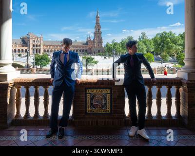 Sevilla, Spanien - 23. April: Zwei Männer in Anzügen stehen auf einem Balkon mit Blick auf einen platz und einen Turm im Hintergrund Stockfoto