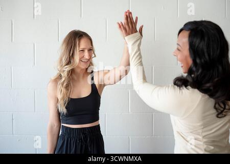 Vielfältige Fitness-Freunde High-Five nach Yoga-Session Stockfoto