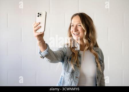 Eine Frau, die ein Selfie in einem Fitnessstudio macht und eine jeansjacke trägt Stockfoto