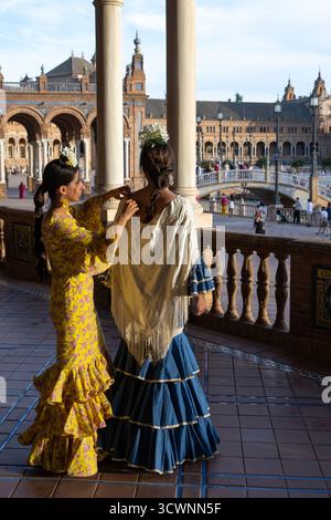 Sevilla, Spanien - 23. April: Zwei Frauen in traditionellen spanischen Kleidern auf einem historischen platz, eine passt die Haare der anderen an, mit einem wunderschönen Architekten Stockfoto