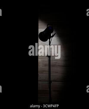 Studio-Spotlight beleuchtet eine Holzwand in einem dunklen Raum. Stockfoto