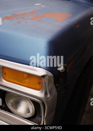 Grobe Nahaufnahme eines verwitterten blauen Vintage Pickups mit Kotflügel und Licht. Verblasste Farben, strukturierte Textur. Ruft Nostalgie und den Lauf der Zeit hervor. Stockfoto