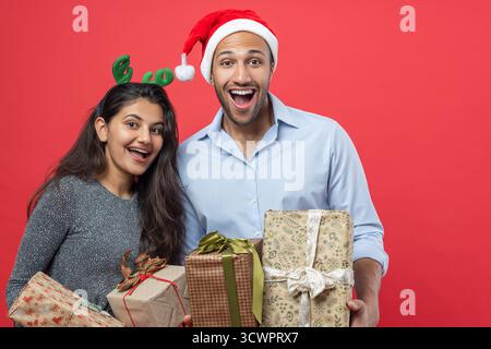 Mann und Frau in festlicher Kleidung feiern Neujahr mit Geschenkboxen und Lametta Stockfoto