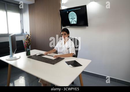 Junge Ärztin bei der Analyse des Röntgenbildes in der minimalistischen Klinik Stockfoto