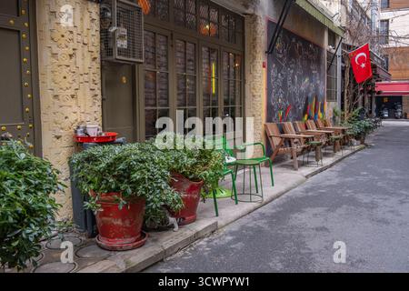 Istanbul, Türkei - 23. März 2023: Farbenfrohes Straßencafé mit Holzstühlen und Tischen vor einer mit Graffiti bedeckten Wand. Straßencafé Stockfoto
