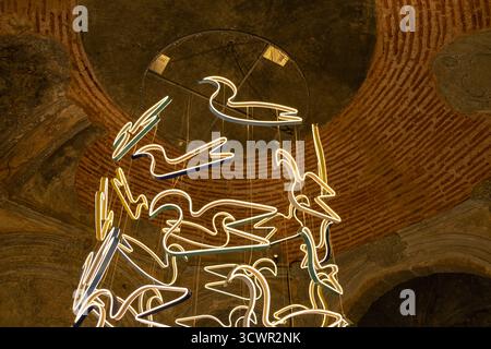 Istanbul, Türkei - 10. März 2023: Installation zeitgenössischer Kunst mit aufgehängten, farbenfrohen Neonskulpturen vor dem Hintergrund einer historischen Backsteinkuppel Stockfoto