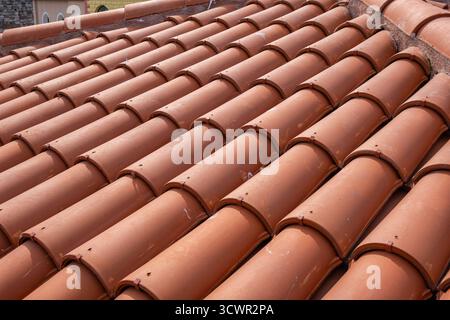 Traditionelle Terrakotta-rote Dachziegel. Klassisches und langlebiges Dach. Alte und benutzte überlappende Muster von warmen Terrakotta-Haus-roten Ton-Fliesen Stockfoto