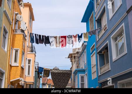 Farbenfrohe Straße in Balat mit Kleidung, die an der Schlange zwischen zwei Häusern hängt. Gewaschene Kleidung hängt und trocknet an Seilen zwischen Wohn b Stockfoto