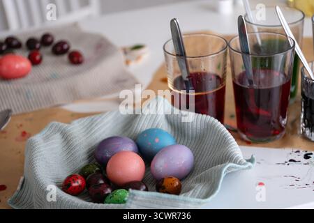 Eine gemütliche Osterserie, in der Kinder zu Hause Eier mit bunten Farben färben. Die Bilder erfassen den gesamten Prozess vom Mischen der Farbstoffe bis zum Halten des Löffels Stockfoto