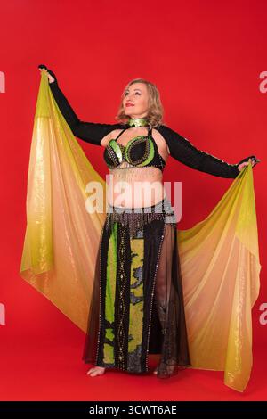 Lächelnde Frau Mode Model mit Pareo in ausgestreckten Armen, Kleid in schwarz-gelb Tanzbühne Kostüm - Bolero, BH-Top und langer Rock mit Stockfoto