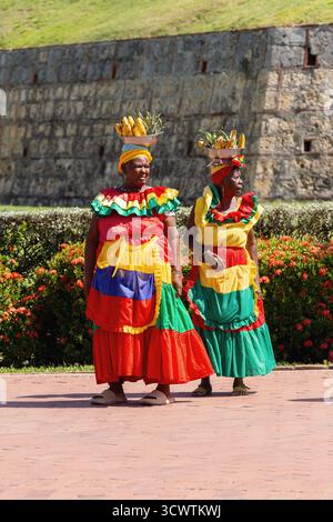 Cartagena de Indias, Kolumbien - 16. Dezember 2023: Zwei Palenquera-Frauen in lebendigen traditionellen Kleidern mit Obstschalen auf dem Kopf in der Nähe der San Stockfoto