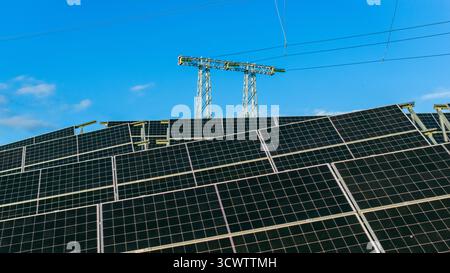 Photovoltaik-Panels, die an Stromleitungen unter blauem Himmel angeschlossen sind Stockfoto