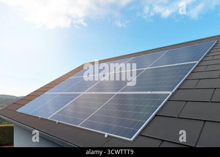 Solarpaneele, die auf einem modernen Hausdach installiert sind und erneuerbare Energie erzeugen Stockfoto