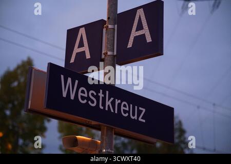 Westkreuz Bahnhofsschild in Berlin bei Dämmerung, beleuchtet unter sanftem Abendlicht mit sichtbaren Oberleitungen. München, Deutschland Stockfoto