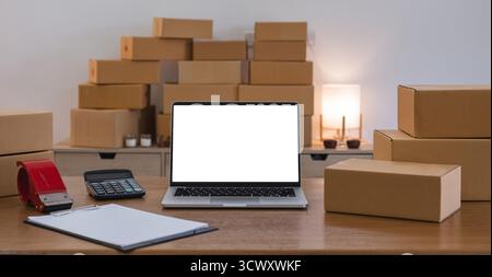 Laptop-Computer am Arbeitsplatz des Start-ups, Inhaber eines kleinen Unternehmens. Papppackung des Produkts zur Lieferung an den Kunden. Online-Verkauf, E-Commerce Stockfoto