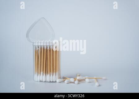 Transparenter Glasbehälter gefüllt mit weißen Wattestäbchen auf einem sauberen weißen Hintergrund. Minimalistische Wohnkultur oder Hygienekonzept in weichem Tageslicht. Stockfoto