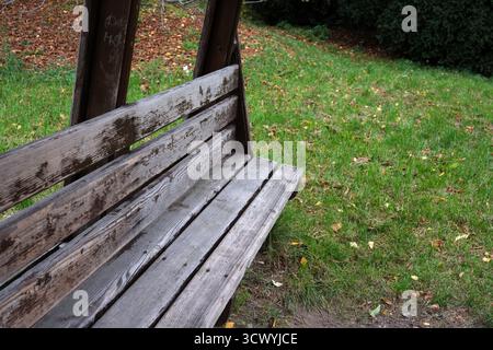 Eine verwitterte Holzbank sitzt ruhig in einem ruhigen Park und lädt zum Entspannen ein. Stockfoto