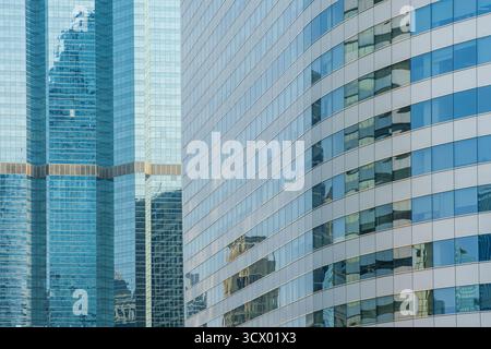 Blick aus nächster Nähe auf moderne Wolkenkratzer mit geschwungenen und reflektierenden Glasfassaden in Bangkok City, Thailand. Abstrakter Architekturhintergrund. Modern Urban Stockfoto