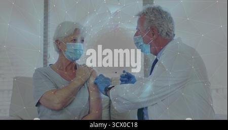 Injizierender Arzt mit Handschuhen, die dem Patienten auf dem Sofa im Klinikraum Impfstoff geben, mit Spritze Stockfoto