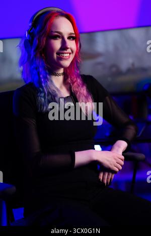 Die junge Frau spielt gern in einer von der Technologie inspirierten Umgebung mit farbenfroher Beleuchtung Stockfoto