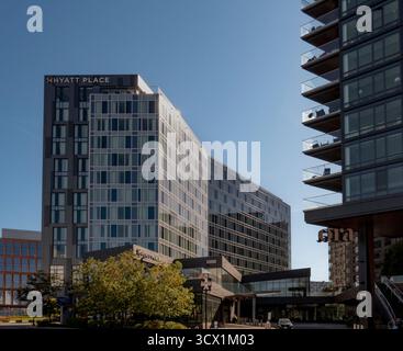 Boston, MA - USA - 2. Oktober 2025 Ein modernes Hyatt Place Hotel und ein Wohngebäude mit Balkonen stehen unter einem klaren blauen Himmel im Seaport Distric Stockfoto