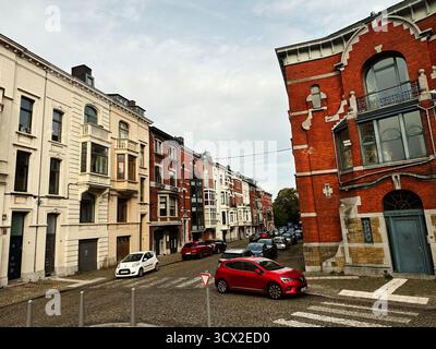 Lüttich, Belgien - 20. Oktober 2023: Charmante Stadtstraße gesäumt von klassischen Stadthäusern und einem auffälligen roten Auto in Lüttich, Belgien. Stockfoto