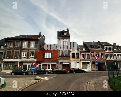 Lüttich, Belgien - 20. Oktober 2023: Reihe von Ziegelhäusern in Lüttich, Belgien mit Autos entlang der Bordsteinkante und klarem Himmel, urbane Atmosphäre. Stockfoto