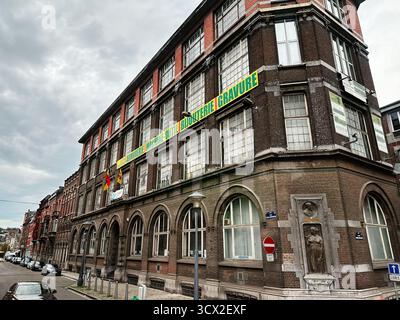 Lüttich, Belgien - 20. Oktober 2023: Backsteingebäude in Lüttich, belgische Straße mit Bogenfenstern und langen Werbeschildern.L'école d'armurerie Léon M Stockfoto