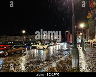 Lüttich, Belgien - 20. Oktober 2023: Ein regnerischer belgischer Stadtplatz in Lüttich bei Nacht mit Verkehr, Reflexionen und leuchtenden Straßenlaternen. Stockfoto