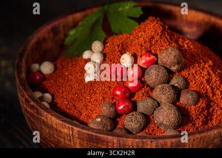 Diese Nahaufnahme zeigt leuchtend roten gemahlenen Pfeffer in einer wunderschön gearbeiteten Holzschale, die seine satte Farbe und Textur betont. Perfekt für Additive Stockfoto