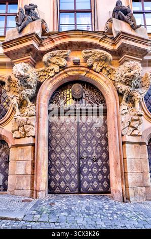 Verzierte schmiedeeiserne Türgriffe und florale Metallarbeiten an einer historischen Holztür in Prag, die gotische und barocke Handwerkskunst zeigt Stockfoto