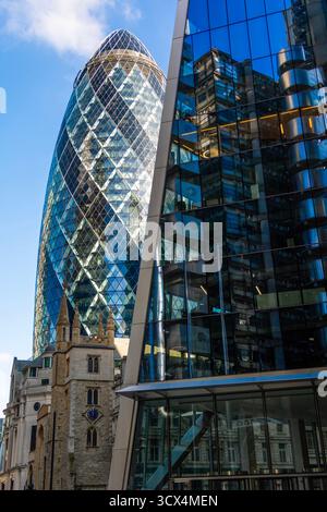 Blick auf den Gherkin (30 St. Mary Axe), der über der St. Helen's Church und hinter dem Skalpell (52-54 Lime Street) thront, der das Lloyd's Building widerspiegelt. Stockfoto