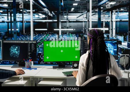 Ingenieure im Rechenzentrum mit Green-Screen-Computern, die Hardware für KI-Aufgaben optimieren und die Workloads erhöhen. IT-Mitarbeiter im Server-Hub automatisieren die Systemdiagnose mithilfe von Deep Learning auf einem Modell-PC Stockfoto