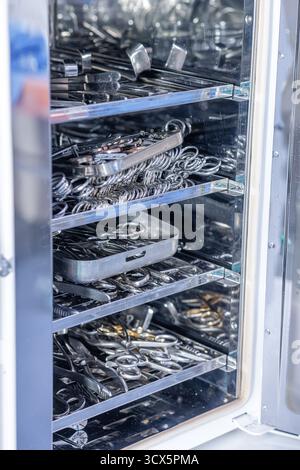 Steriler Prozessschrank gefüllt mit rostfreien chirurgischen Werkzeugen und Tabletts, ideal für Schulungen im Gesundheitswesen, Sicherheitsmaterialien und Medtech-Kataloge. Stockfoto