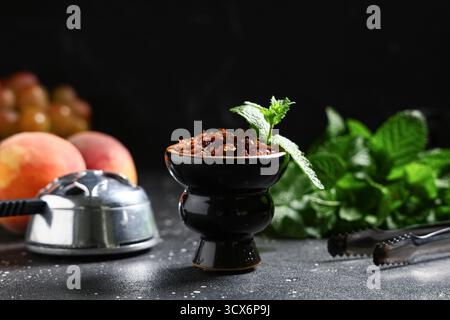 Shisha Schüssel Tabak mit Früchten und Minzblättern auf schwarzem Hintergrund Stockfoto