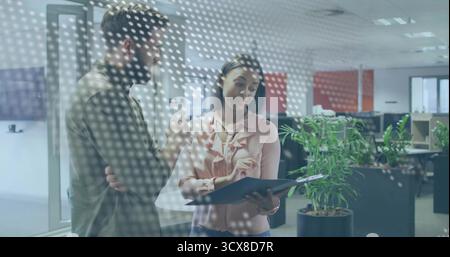 Kollegen in olivrosa Kleidung, die den Plan im Büro hinter einer gepunkteten Glasscheibe mit Tablet überprüfen Stockfoto