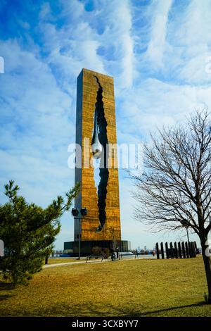 Das Tears Drop Memorial in Bayonne, New Jersey, steht hoch unter einem leuchtend blauen Himmel, dessen reflektierende Skulptur Frieden, Erinnerung und Einheit symbolisiert Stockfoto