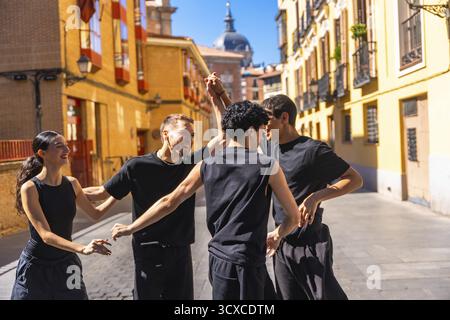 Gruppe junger Freunde, die eine zeitgenössische urbane Tanzvorstellung genießen und Freude und Freiheit ausdrücken, während sie sich auf einer sonnigen Straße in madrid bewegen Stockfoto
