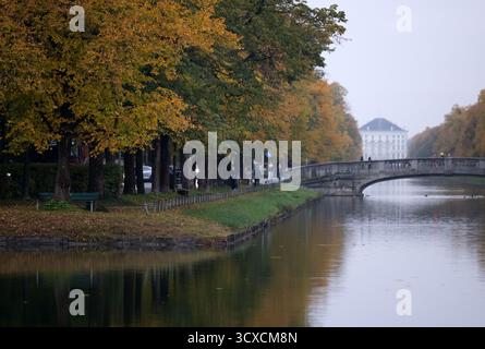 München, Deutschland. Oktober 2025. Am Nymphenburger Kanal stehen herbstliche Bäume. Das Schloss Nymphenburg ist im Hintergrund zu sehen. Quelle: Sven Hoppe/dpa/Alamy Live News Stockfoto