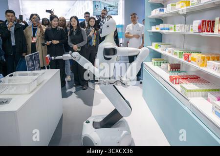 Peking, China. Oktober 2025. Repräsentanten, die zum Global Leaders' Meeting on Women in Peking sind, beobachten einen Roboter, der Medizin in der Beijing World of Robots in Peking, der Hauptstadt Chinas, am 14. Oktober 2025 holt. Quelle: Du Zixuan/Xinhua/Alamy Live News Stockfoto