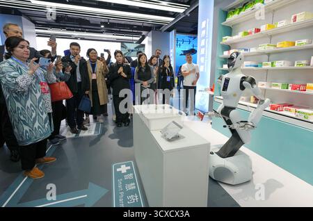 Peking, China. Oktober 2025. Repräsentanten, die zum Global Leaders' Meeting on Women in Peking sind, beobachten einen Roboter, der Medizin in der Beijing World of Robots in Peking, der Hauptstadt Chinas, am 14. Oktober 2025 holt. Quelle: Xue Yuge/Xinhua/Alamy Live News Stockfoto