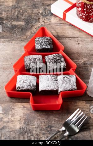 Schokoladen-Brownies mit Puderzucker in Tannenschale auf Holztisch Stockfoto