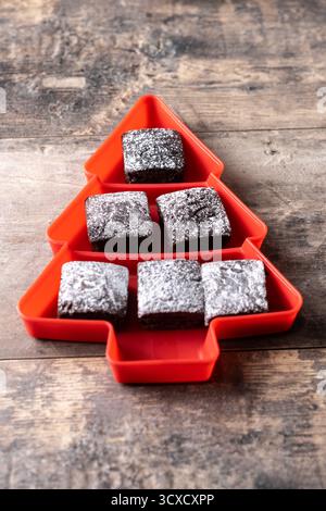 Schokoladen-Brownies mit Puderzucker in Tannenschale auf Holztisch Stockfoto