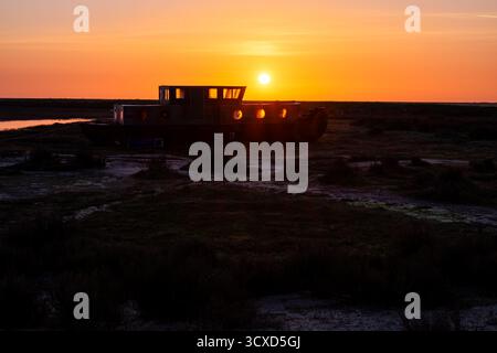 Sonnenaufgang über einem alten Schiffswrack auf den Salzwiesen in der Nähe von Blakeney in Norfolk Stockfoto