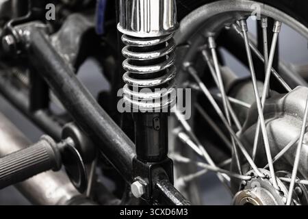 Nahaufnahme einer Motorradaufhängung mit Chromfeder, Gabel und Speichenrad. Die robusten Metallstrukturen vermitteln mechanische Präzision Stockfoto
