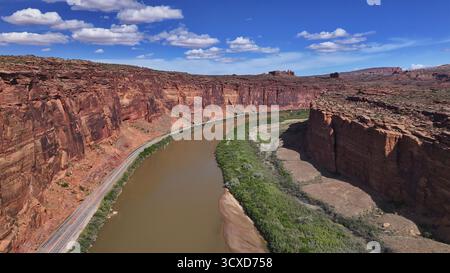 Der sich windende Fluss aus der Vogelperspektive durchzieht die rötlich-braunen Canyons unter einem teilweise bewölkten Himmel und offenbart die raue Schönheit des amerikanischen Südwestens, Moab, Utah, USA. Stockfoto