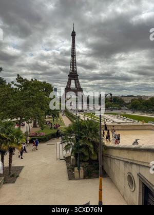 Großer erhöhter Blick vom Eiffelturm aus den Trocadéro-Gärten, Paris. Touristen wandern zwischen Terrassen, Springbrunnen und bewölktem dramatischem Himmel. Stockfoto