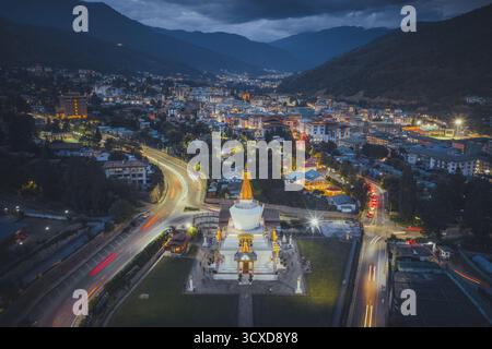 Blick aus der Vogelperspektive auf das National Memorial Chorten, beleuchtet vor dem Hintergrund der Lichter der Stadt und der dunklen Silhouette der Berge, Thimphu, Bhutan. Stockfoto