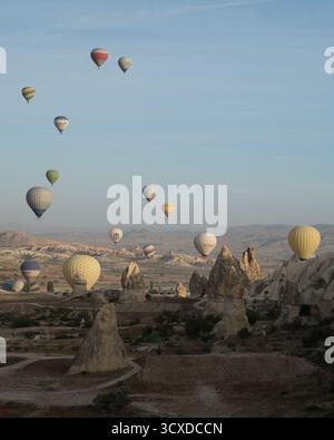 Goreme, Turkiye - 11. Oktober 2019: Der Blick auf Heißluftballons driftet ruhig über die jenseitige Landschaft Kappadokiens, gebadet im weichen, goldenen l Stockfoto